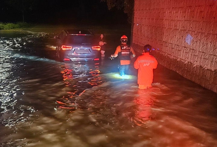 A vehicle is submerged due to heavy rain on a road in Damyang, South Jeolla Province, as fire authorities carry out drainage operations Sunday. (Newsis)